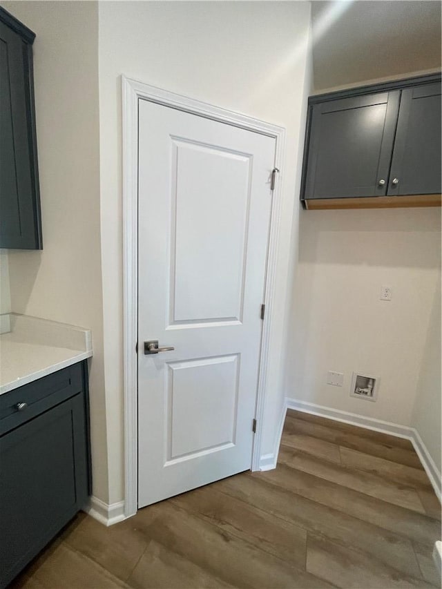 laundry room with baseboards and wood finished floors