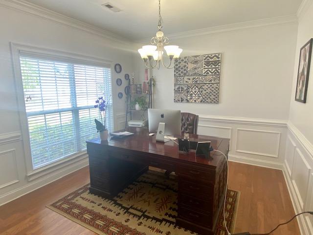 office featuring wood finished floors, visible vents, a notable chandelier, and ornamental molding