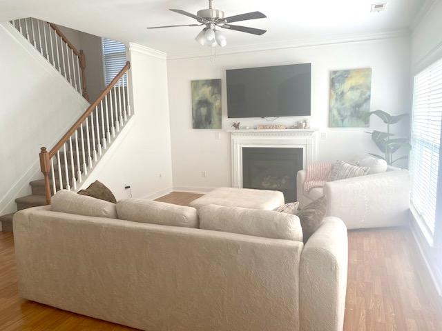 living room featuring stairway, ceiling fan, a wealth of natural light, and wood finished floors