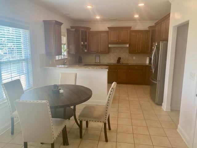 kitchen with decorative backsplash, freestanding refrigerator, glass insert cabinets, and a healthy amount of sunlight