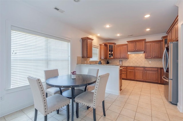 118 Easy Gap Rd, Anderson, SC 29621 - kitchen featuring freestanding refrigerator, brown cabinets, glass insert cabinets, decorative backsplash, and light stone countertops