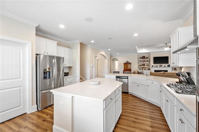 kitchen featuring a sink, open floor plan, ceiling fan, arched walkways, and stainless steel appliances