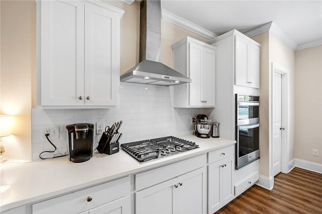 kitchen with wall chimney exhaust hood, stainless steel appliances, backsplash, and ornamental molding