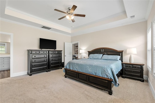 carpeted bedroom with visible vents, a tray ceiling, and crown molding