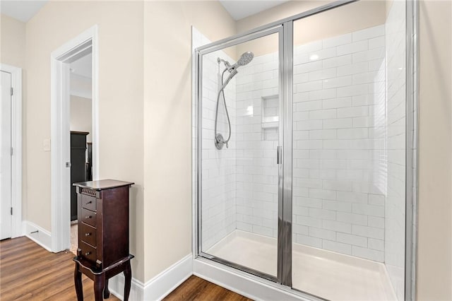 full bath with a shower stall, baseboards, and wood finished floors