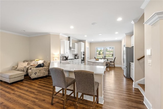 kitchen with a kitchen breakfast bar, stainless steel appliances, light countertops, ornamental molding, and white cabinetry