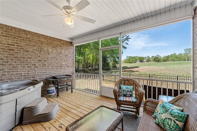 sunroom featuring ceiling fan, a wealth of natural light, and a jacuzzi