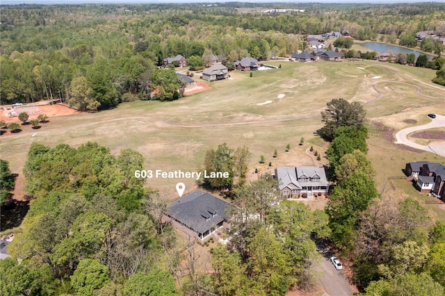 birds eye view of property with view of golf course, a view of trees, a water view, and a residential view