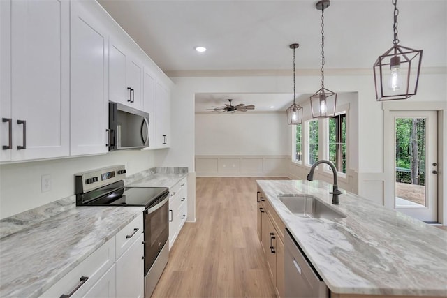 138 Jackson Cir, Anderson, SC 29625 - kitchen featuring a wainscoted wall, stainless steel appliances, a sink, a kitchen island with sink, and light wood-style flooring