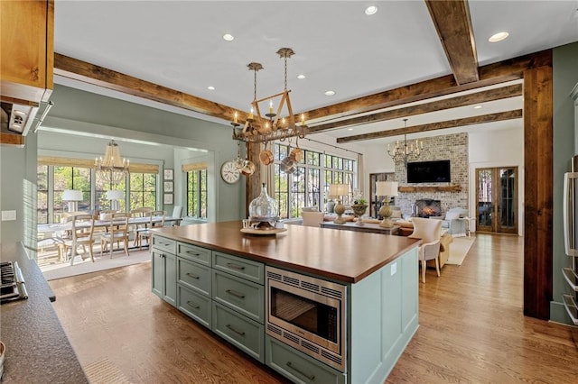 211 Quay Ct, Sunset, SC 29685 - kitchen featuring stainless steel microwave, light wood-type flooring, a notable chandelier, beamed ceiling, and a fireplace
