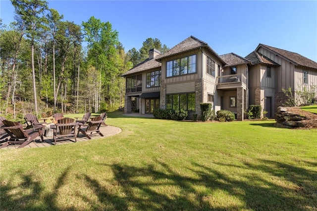 211 Quay Ct, Sunset, SC 29685 - back of property featuring a balcony, a lawn, a chimney, board and batten siding, and an outdoor fire pit