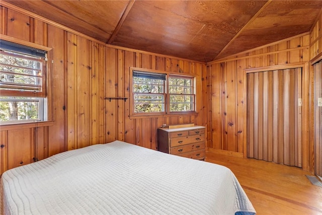 bedroom with wooden ceiling, multiple windows, wooden walls, and light wood-style flooring