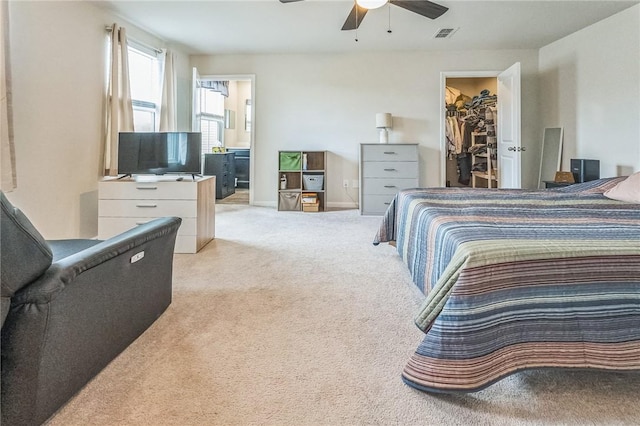 bedroom featuring a closet, visible vents, ceiling fan, carpet floors, and a walk in closet