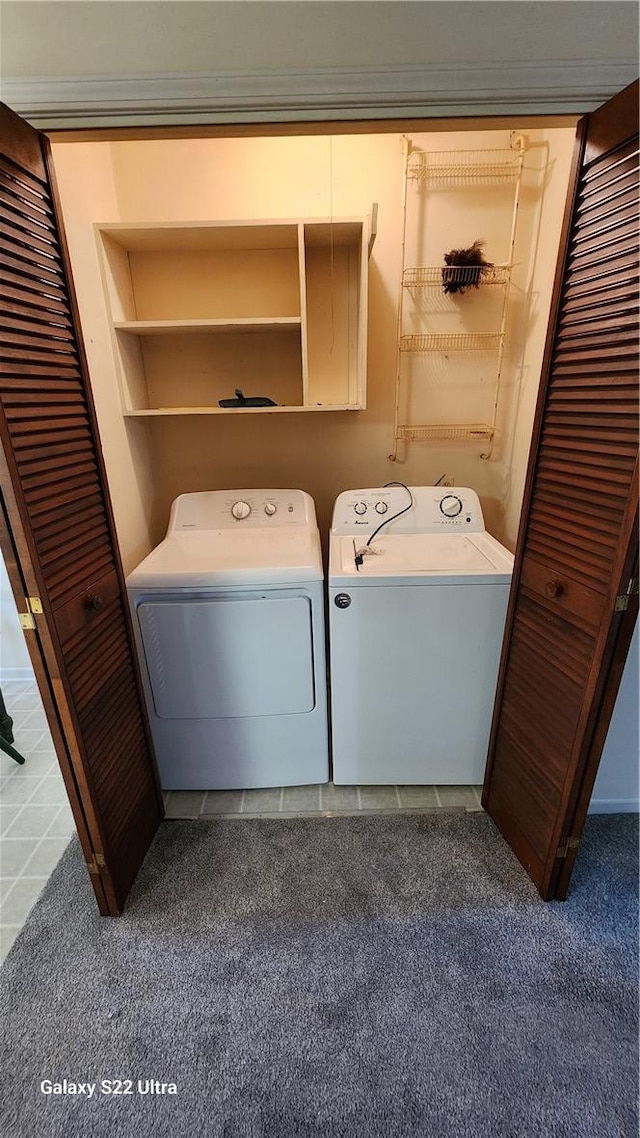 laundry area with dark colored carpet, washer and dryer, dark tile patterned flooring, and laundry area