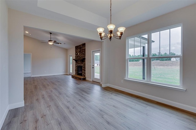 unfurnished living room featuring lofted ceiling, a chandelier, wood finished floors, baseboards, and a fireplace