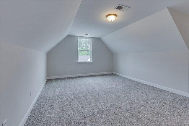 additional living space featuring carpet floors, lofted ceiling, and baseboards