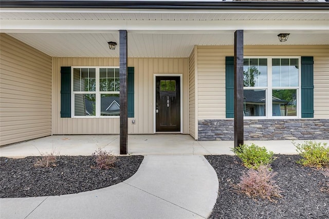 view of exterior entry featuring covered porch and stone siding