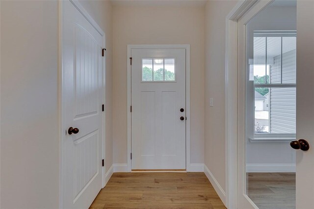 doorway with light wood-style floors and baseboards