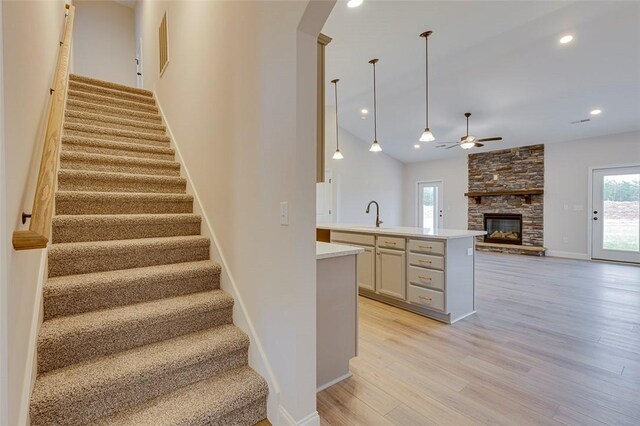 stairs with ceiling fan, a fireplace, wood finished floors, baseboards, and recessed lighting
