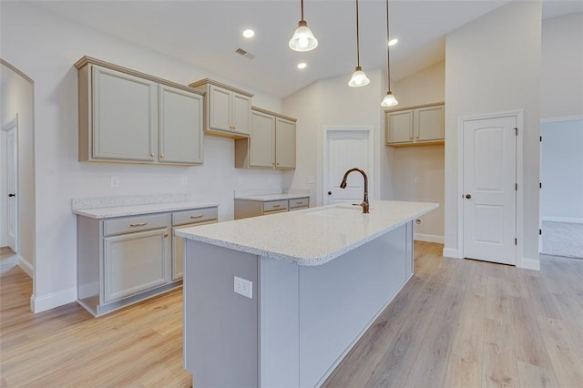 kitchen with a sink, light wood-style flooring, baseboards, vaulted ceiling, and recessed lighting