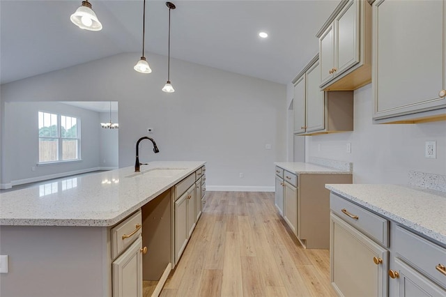 kitchen with a sink, light wood-style flooring, lofted ceiling, light stone counters, and dishwasher