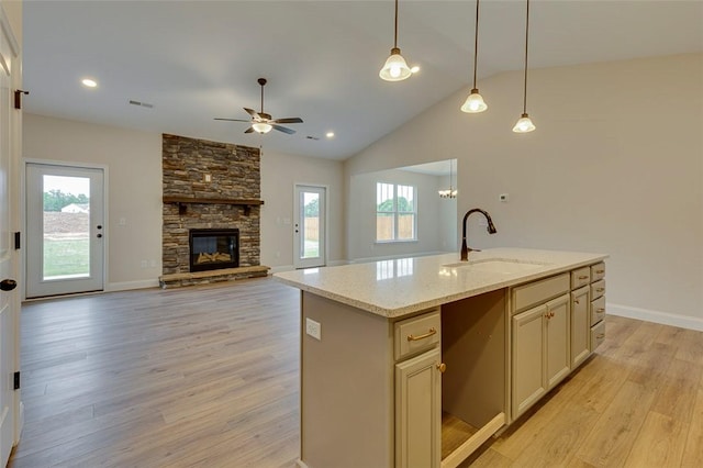 kitchen with a sink, ceiling fan, light wood-style flooring, hanging light fixtures, and vaulted ceiling