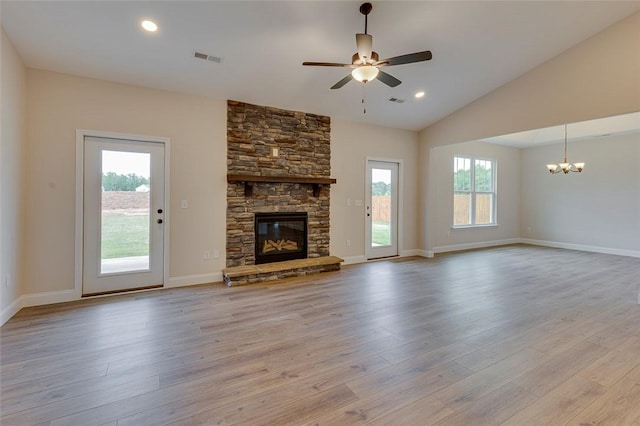 unfurnished living room featuring a chandelier, ceiling fan, plenty of natural light, wood finished floors, and lofted ceiling