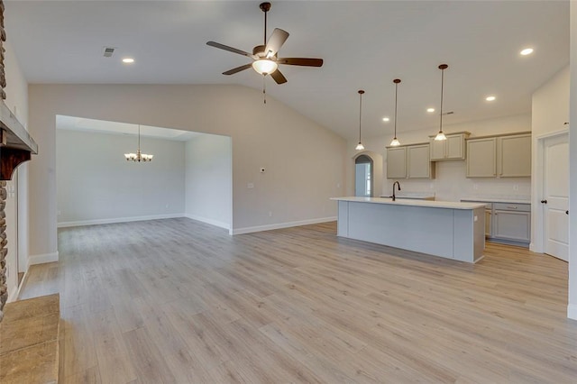 kitchen featuring ceiling fan, vaulted ceiling, open floor plan, a chandelier, and light countertops