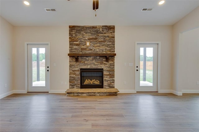 unfurnished living room with ceiling fan, wood-type flooring, a stone fireplace, baseboards, and recessed lighting