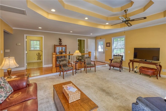 carpeted living area featuring baseboards, visible vents, a wealth of natural light, and ornamental molding