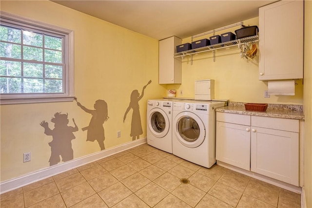 clothes washing area featuring baseboards, independent washer and dryer, light tile patterned floors, and cabinet space