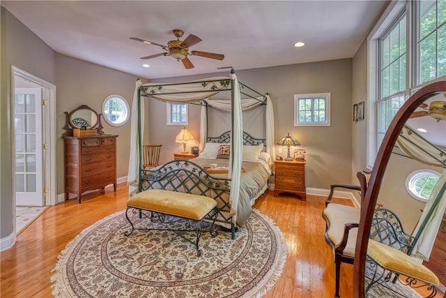 bedroom featuring light wood-style floors, ceiling fan, baseboards, and multiple windows