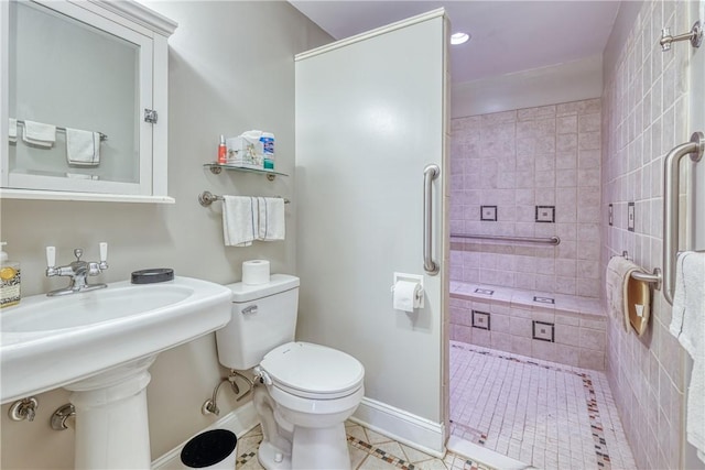 bathroom with a sink, walk in shower, baseboards, toilet, and tile patterned flooring