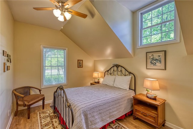 bedroom with vaulted ceiling, baseboards, multiple windows, and light wood-type flooring