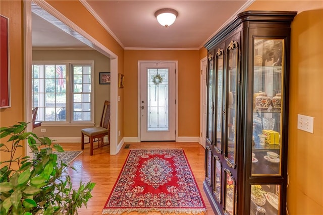 foyer with baseboards, ornamental molding, and light wood finished floors