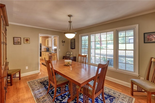 dining space featuring light wood-style flooring, baseboards, and ornamental molding