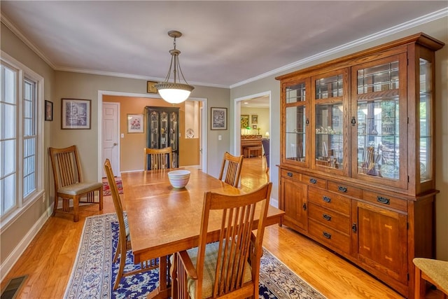 dining space featuring baseboards, crown molding, visible vents, and light wood-type flooring
