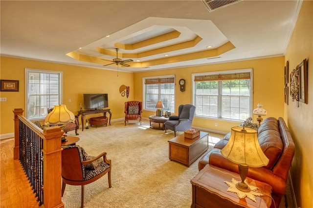living area featuring baseboards, visible vents, a raised ceiling, and crown molding