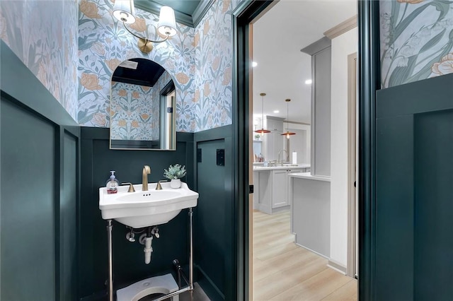 bathroom with wallpapered walls, wood finished floors, and a sink