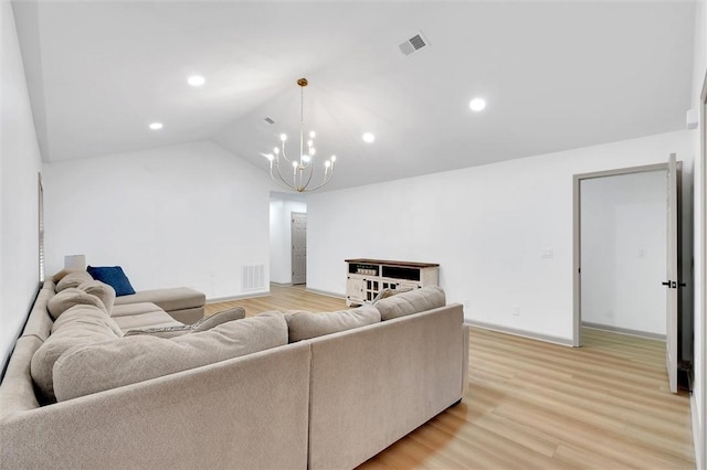 living room featuring light wood-type flooring, vaulted ceiling, visible vents, and a chandelier