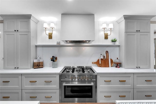 kitchen with gray cabinets, high end stainless steel range oven, light countertops, and custom range hood