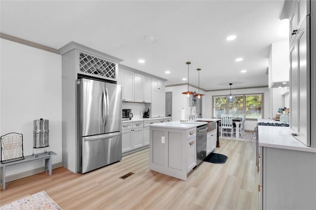 kitchen featuring light wood finished floors, stainless steel appliances, visible vents, and light countertops