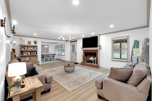 living room featuring light wood finished floors, a brick fireplace, recessed lighting, and a chandelier