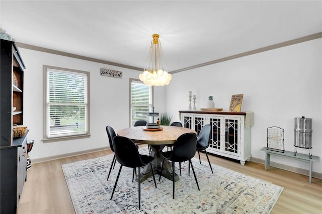 dining area with light wood finished floors, baseboards, a notable chandelier, and crown molding