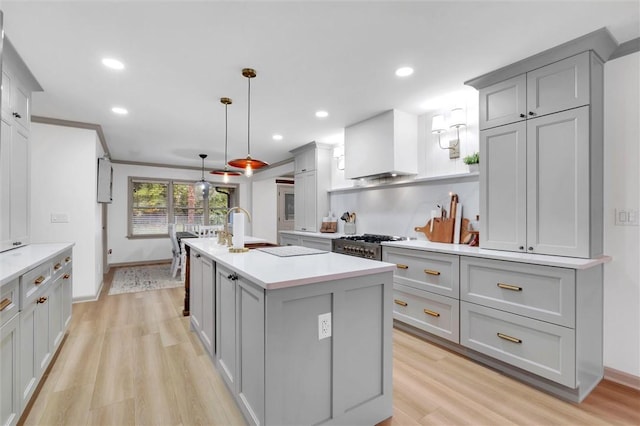 kitchen featuring gray cabinets, a sink, light countertops, and custom range hood