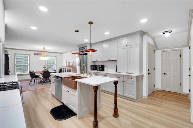 kitchen featuring stainless steel appliances, a sink, light countertops, and light wood-style flooring
