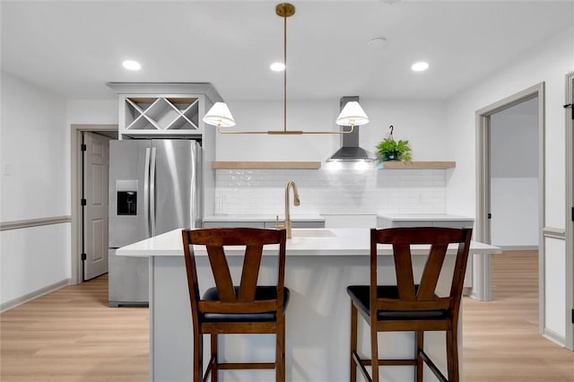 kitchen featuring tasteful backsplash, open shelves, a sink, stainless steel fridge, and light wood-style flooring