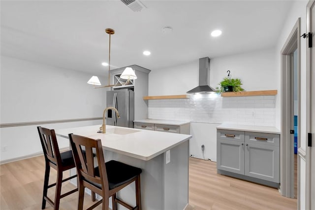 kitchen with open shelves, gray cabinets, wall chimney exhaust hood, tasteful backsplash, and stainless steel refrigerator with ice dispenser