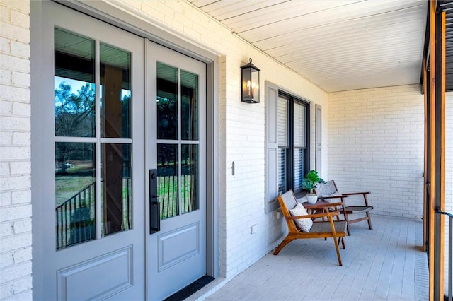 entrance to property featuring brick siding, french doors, and a porch