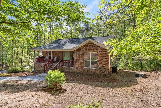 single story home with brick siding, cooling unit, a shingled roof, and covered porch